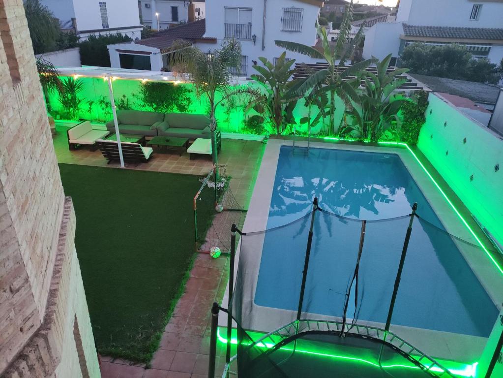 - une vue sur la piscine avec éclairage vert dans l'établissement Apartamento privado con piscina y jardin compartidos., à Valencina de la Concepción