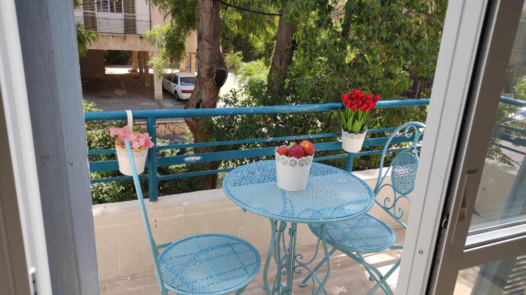 a table and two chairs with flowers on a balcony at Lovely studio with balcony in Rechovot