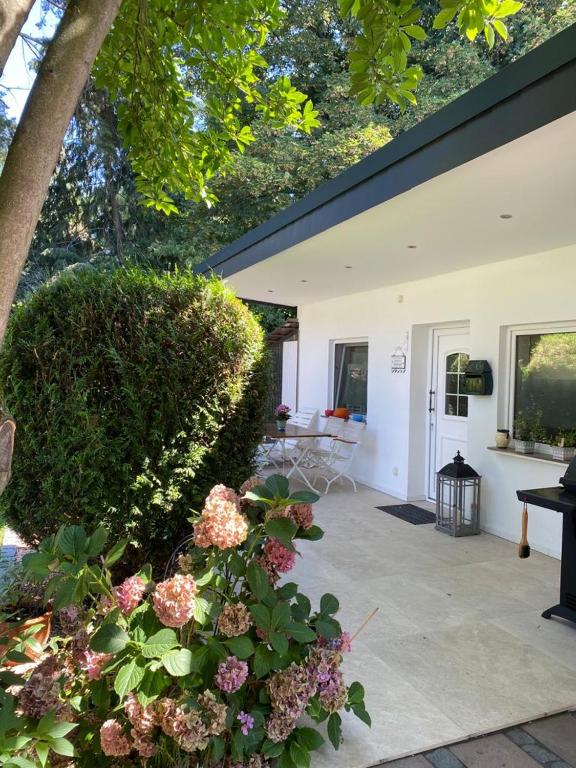 a house with a patio with flowers in front of it at Boardinghouse Meerbusch, Ihr privater Bungalow, nahe Messe Düsseldorf in Meerbusch