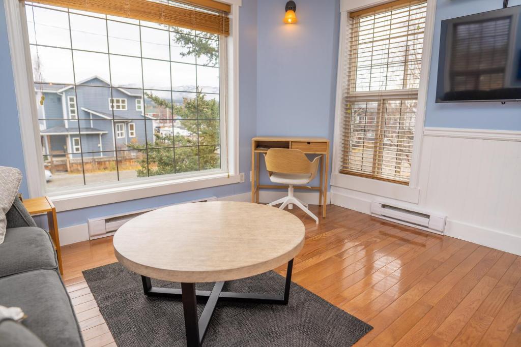 a living room with a table and two windows at Downtown Whitehorse Apartment in Old Town in Whitehorse