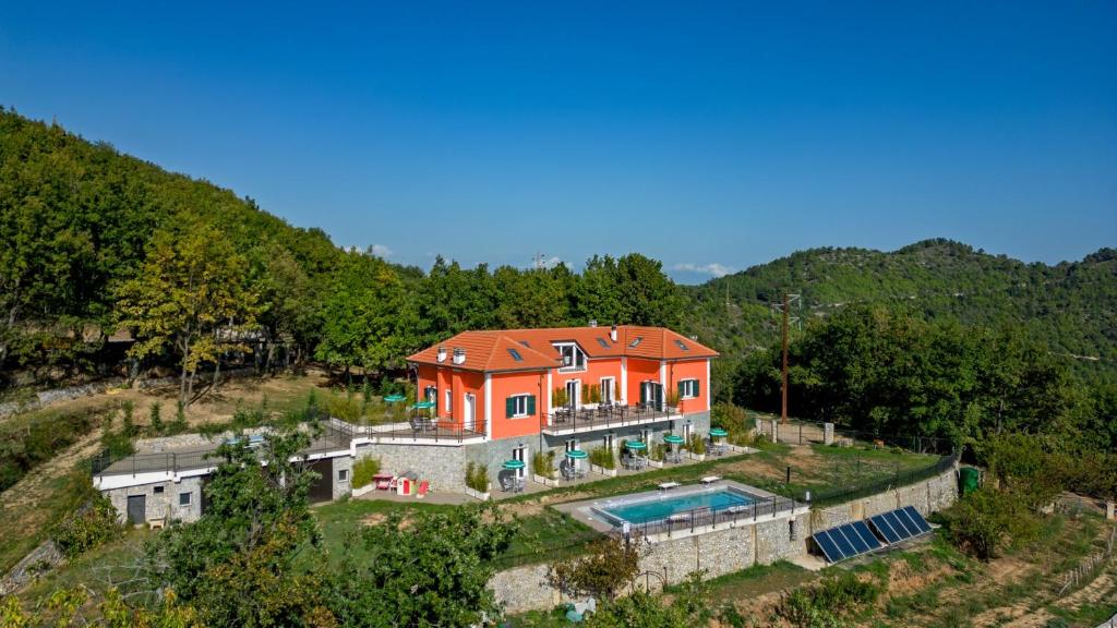 une maison orange avec une piscine sur une colline dans l'établissement Agriturismo Cascina Trevo, à Spotorno