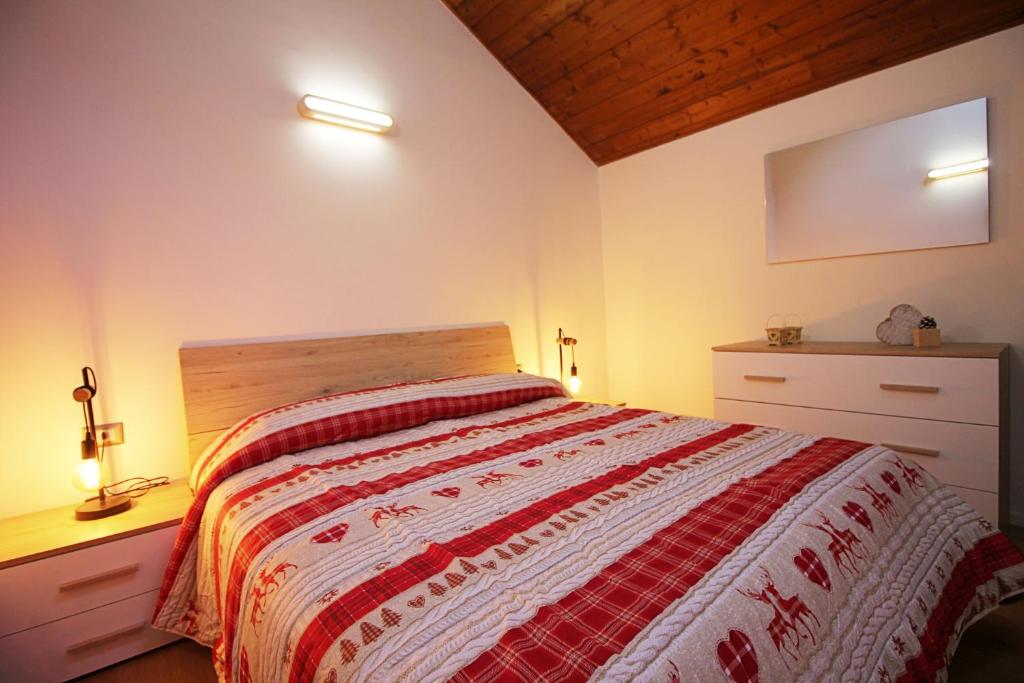 a bedroom with a bed with a red and white blanket at IL CERVO - Cavalese Olimpiadi 2026, Dolomiti Affitti in Cavalese