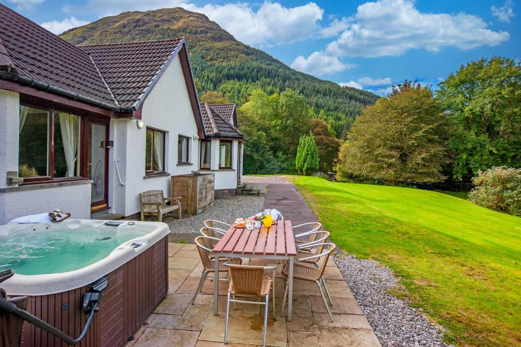 a patio with a table and a bath tub at Wildwood Cottage with Hot Tub in Glencoe