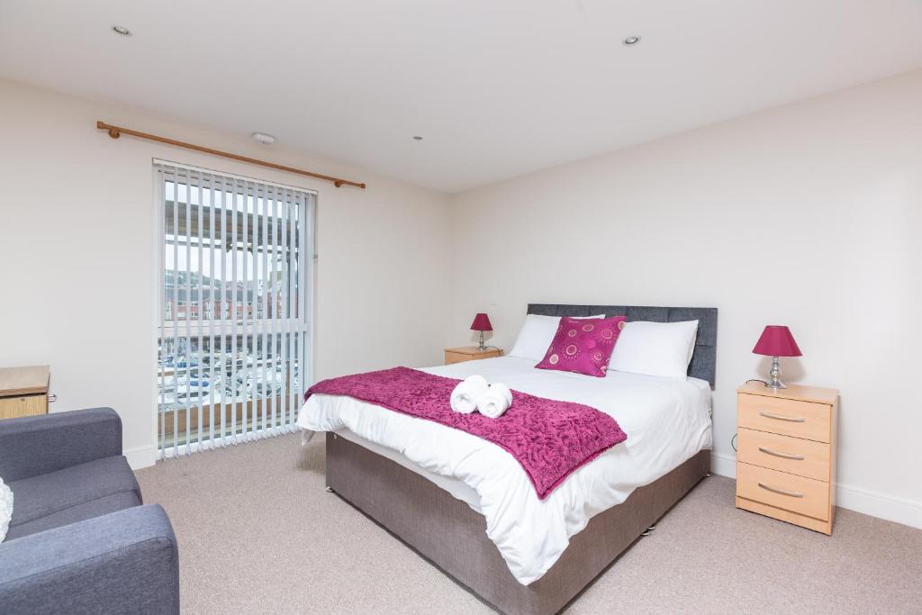 a bedroom with a bed with a teddy bear on it at Marina View Apartment in Swansea
