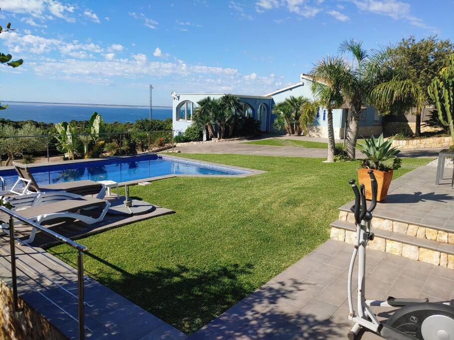 a house with a swimming pool and a lawn with chairs at Chalet privado, con vistas al mar. in Perelló