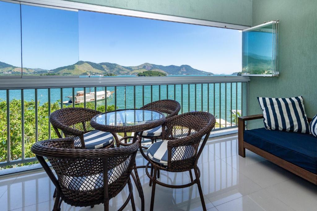 a balcony with a table and chairs and a view of the water at Requinte à beira mar! Recarregue suas energias! in Angra dos Reis