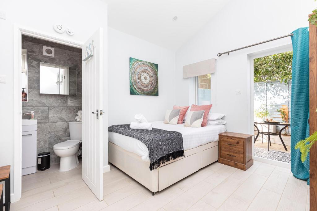 a white bedroom with a bed and a bathroom at Stylish studio flat with private patio and free on-street parking in Bournemouth