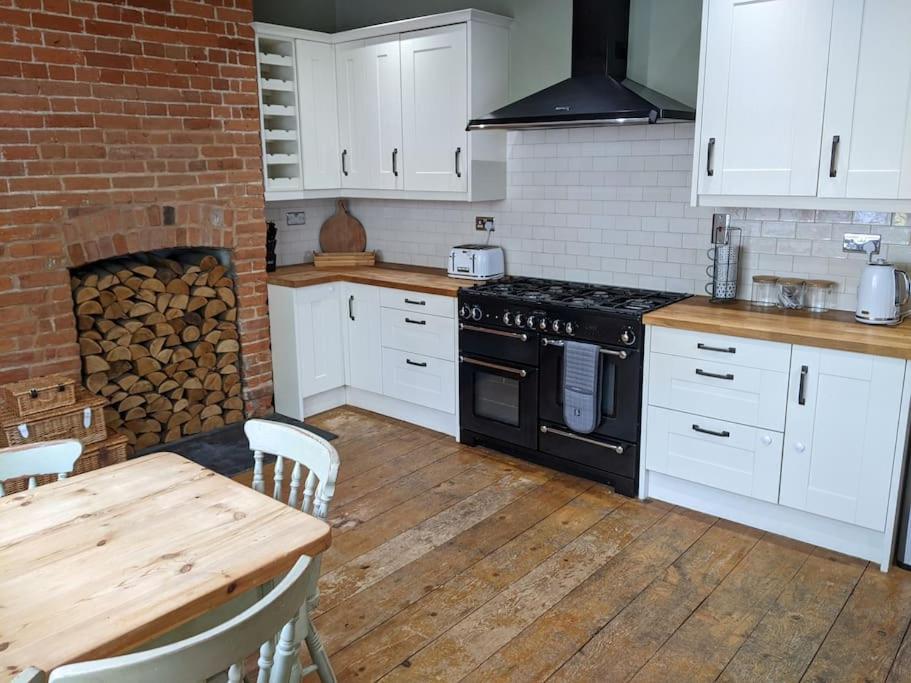 una cucina con piano cottura, tavolo e muro di mattoni di Beautiful Georgian townhouse in central Colchester a Colchester