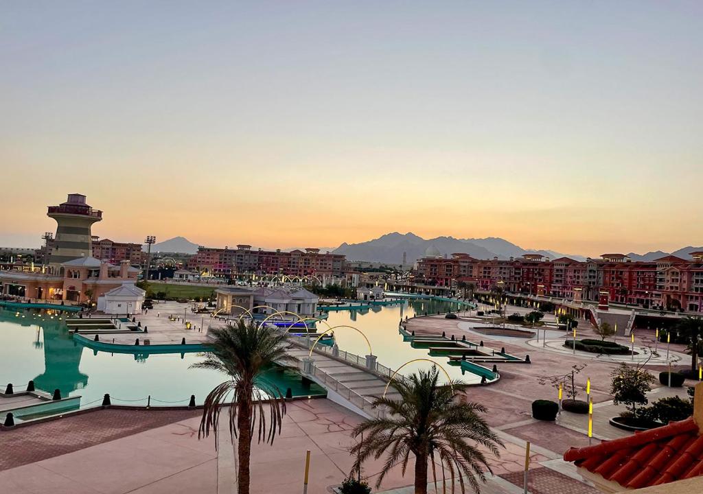 a resort with a pool and buildings and palm trees at Fully Equipped Apartments Pool & Mountains View in Porto Sharm Resort in Sharm El Sheikh