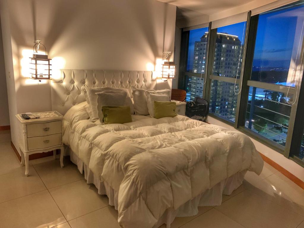 a bedroom with a large bed with a large window at Torre Tressesenta Apto 1508 in Punta del Este