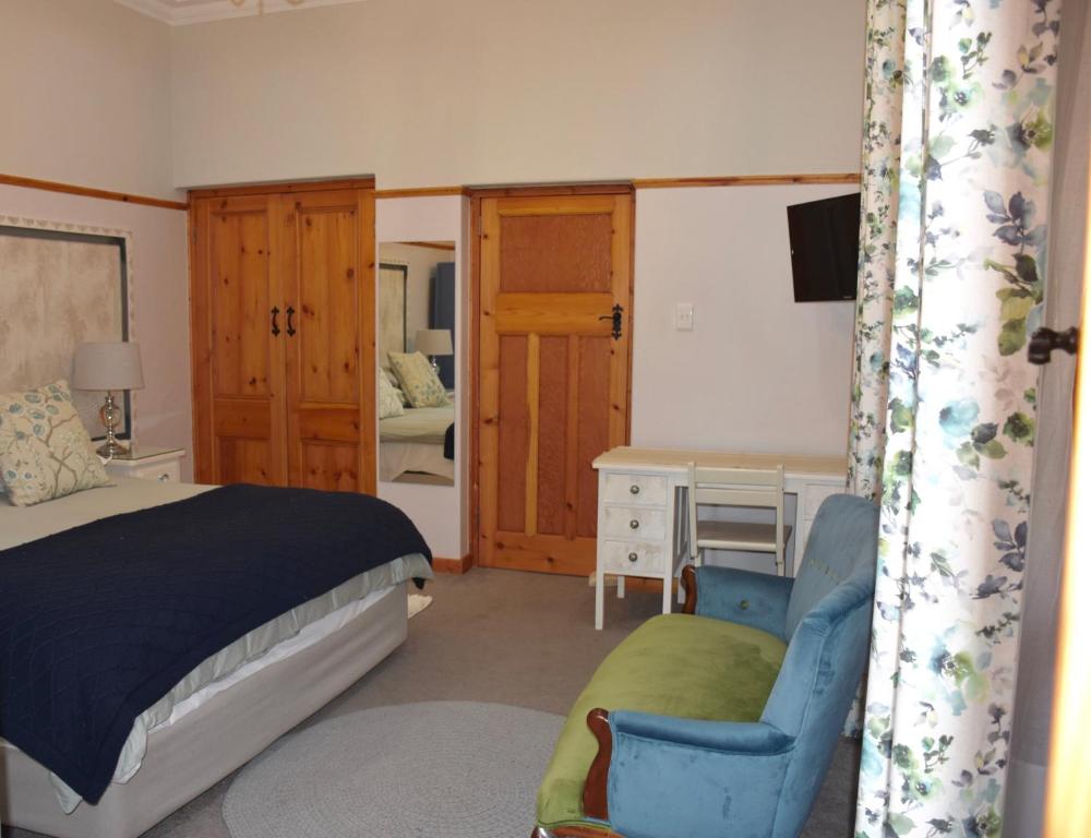 a bedroom with a bed and a chair and a desk at Luxury and homely stay in Oudtshoorn