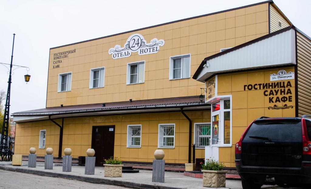 żółty budynek z samochodem zaparkowanym przed nim w obiekcie "Отель 24 часа" w mieście Barnauł