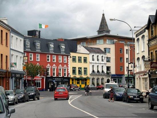 a busy city street with cars parked on the road at Killarney Town Apartment in Killarney