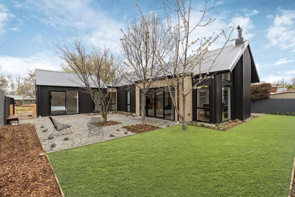 una casa nera con un prato davanti di Luxe Arrowtown Home ad Arrowtown