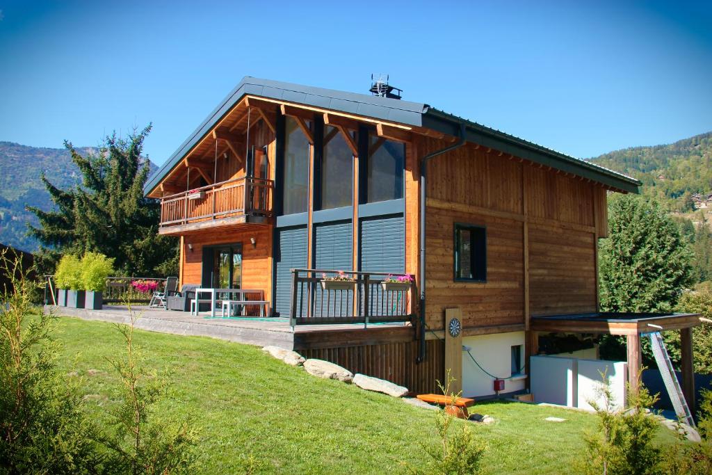 ein großes Holzhaus auf einem Hügel mit Hof in der Unterkunft Chalet Amour blanc in Les Houches
