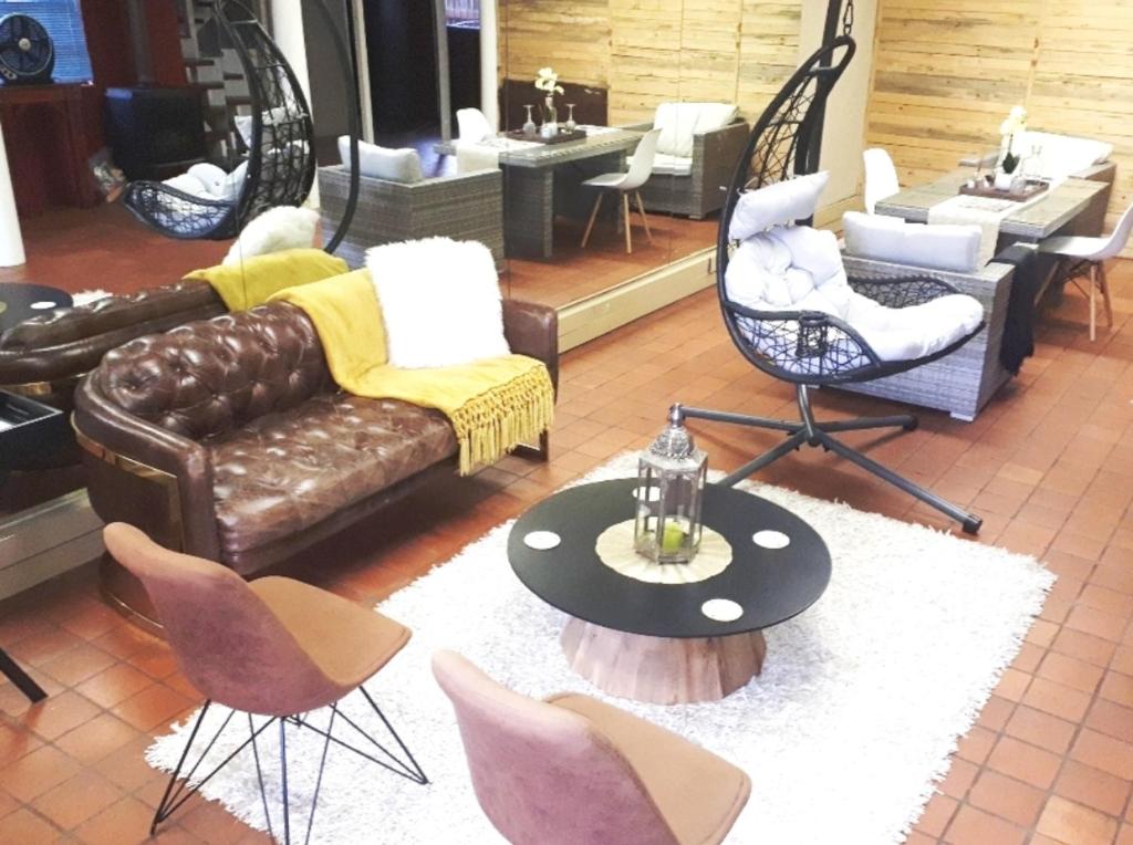 een woonkamer met een bank, stoelen en een tafel bij The Gallery Guest House in Port Elizabeth