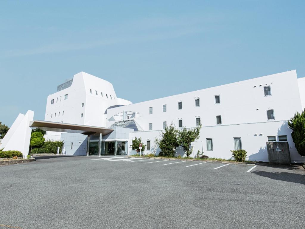 淡路的住宿－KAMENOI HOTEL Awajishima，白色建筑前的一个空停车位