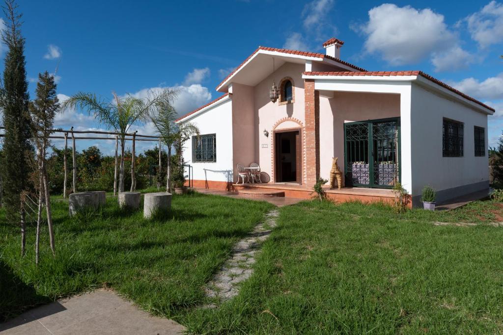 a small white house with a green yard at Dar Ghita en campagne in O Ben Slimane