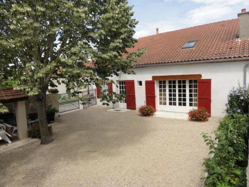 ein Haus mit roten Türen und einer Auffahrt in der Unterkunft Gîte Charroux - Allier, 4 pièces, 7 personnes - FR-1-489-271 in Charroux-dʼAllier