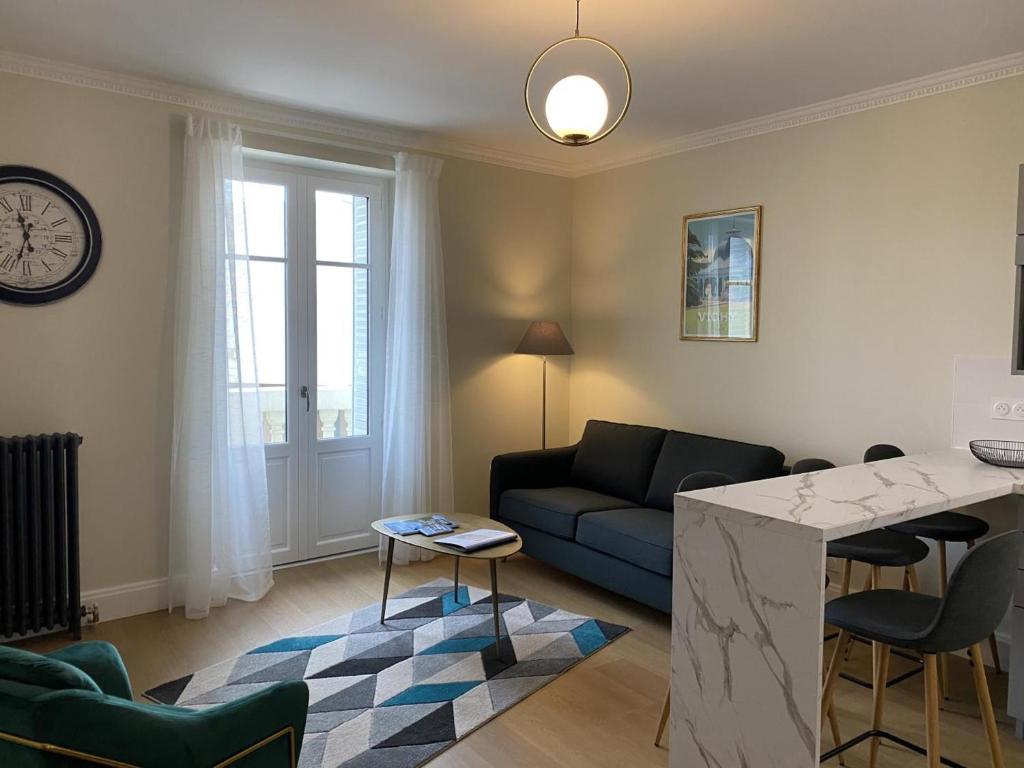 ein Wohnzimmer mit Sofa und Tisch in der Unterkunft Appartement cosy au cœur de Vichy, proche thermes et commerces, tout inclus, idéal 2 pers. + options - FR-1-489-364 in Vichy