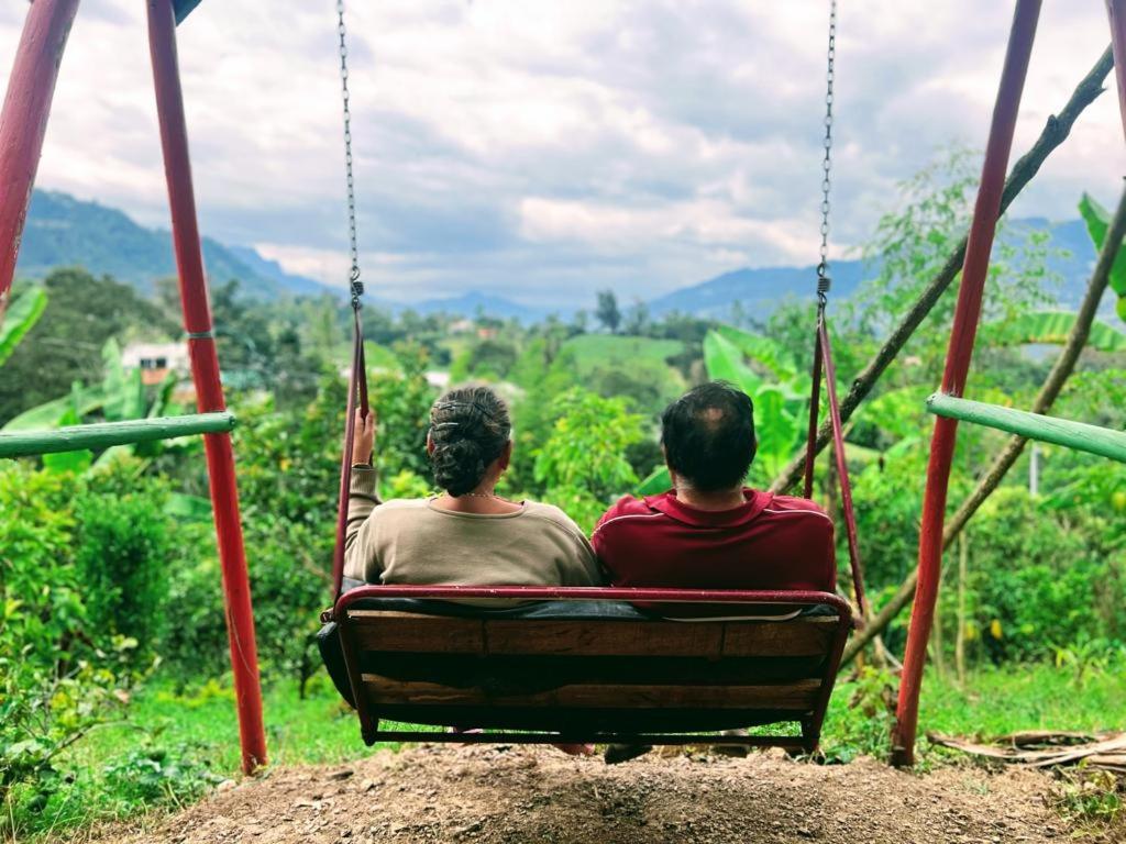 two people sitting on a swing looking out at the mountains at Posada Lu.Lu in Choachí