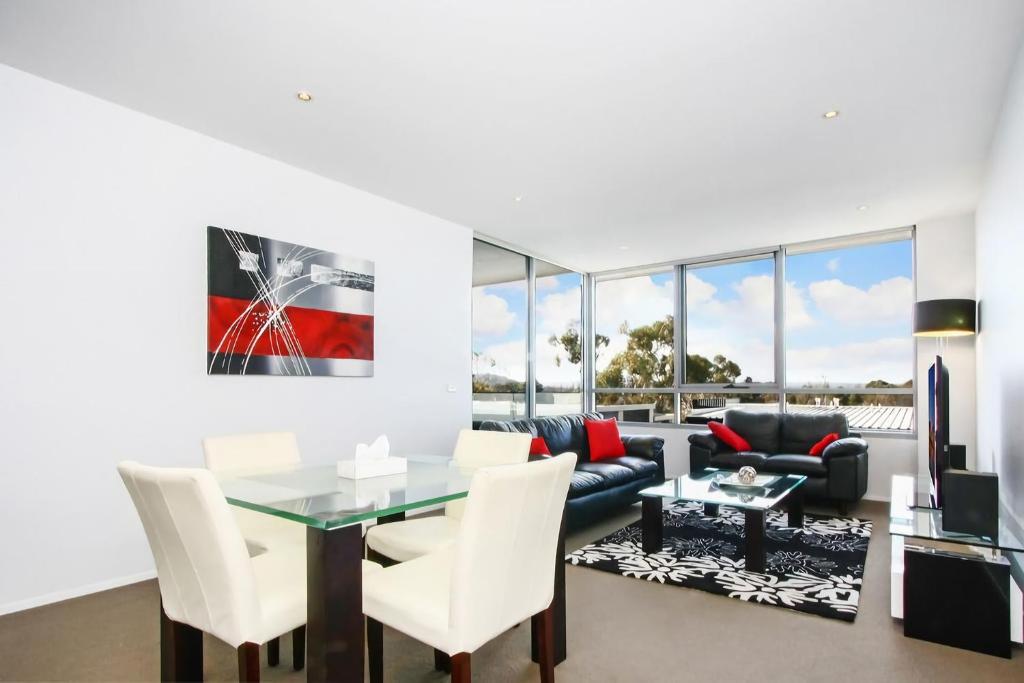 a living room with a glass table and white chairs at Accommodate Canberra - Realm Residences in Canberra
