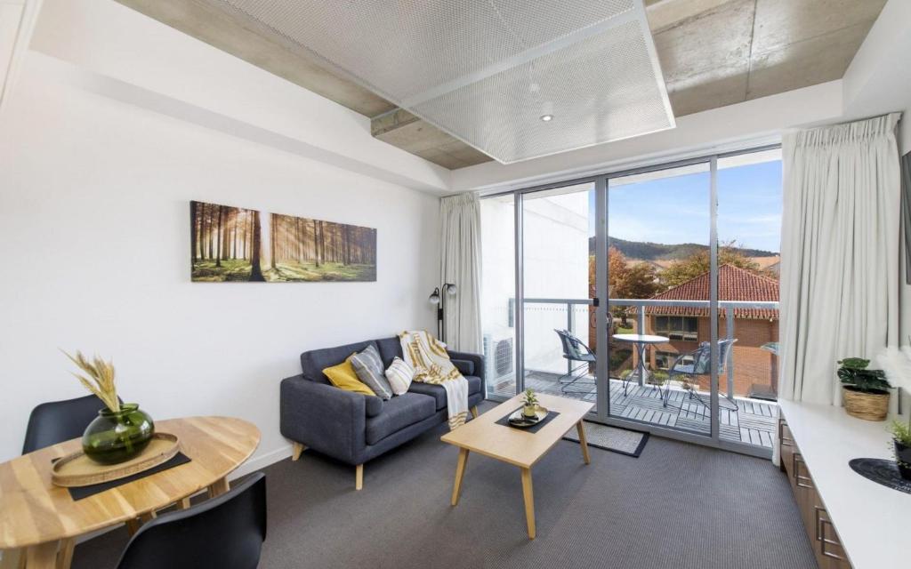 a living room with a couch and a table at Mode Apartments Braddon ACT in Canberra