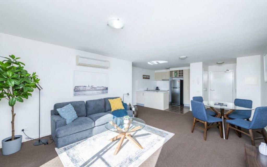 a living room with a blue couch and a table at Century 23 Griffith in Canberra