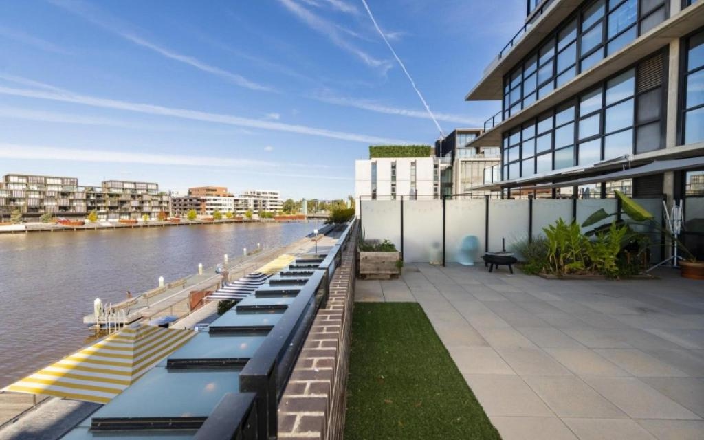 une rangée de bancs près d'une rivière avec des bâtiments dans l'établissement Dockside Apartments Kingston ACT, à Canberra