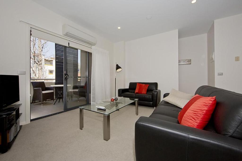 een woonkamer met een zwarte bank en een tafel bij Domain 8 Deakin ACT in Canberra