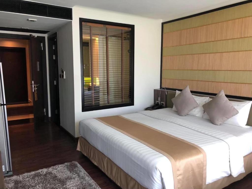 een slaapkamer met een groot bed en een groot raam bij The Beach by Glitter House in Kata Beach