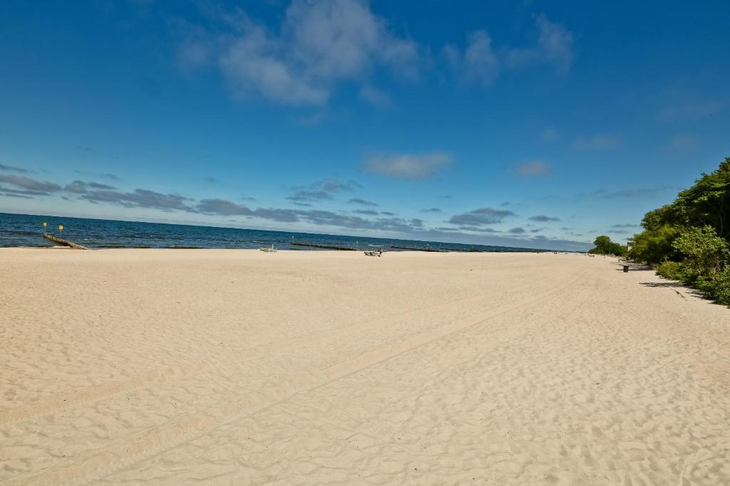 ein Sandstrand mit dem Meer im Hintergrund in der Unterkunft Diune Resort & Apartamenty in Kołobrzeg