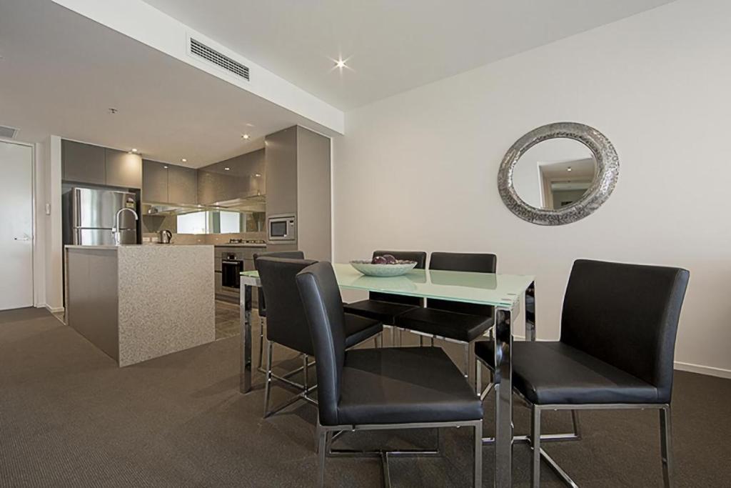 a dining room with a table and chairs and a kitchen at Manhattan 303 Canberra City ACT in Canberra