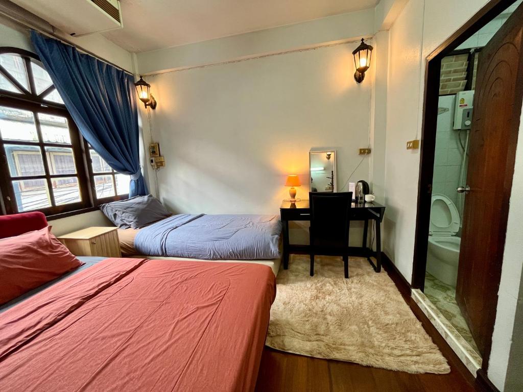 1 dormitorio con 2 camas, escritorio y baño en C U Again, en Bangkok