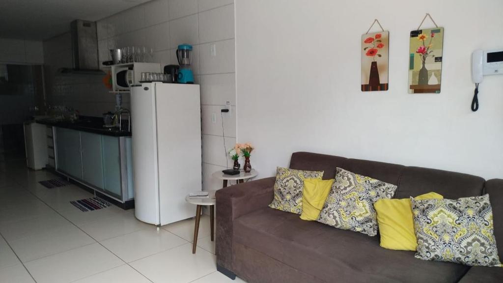 a living room with a brown couch and a refrigerator at Casa com 2 quartos e banheira de Hidromassagem in Trindade