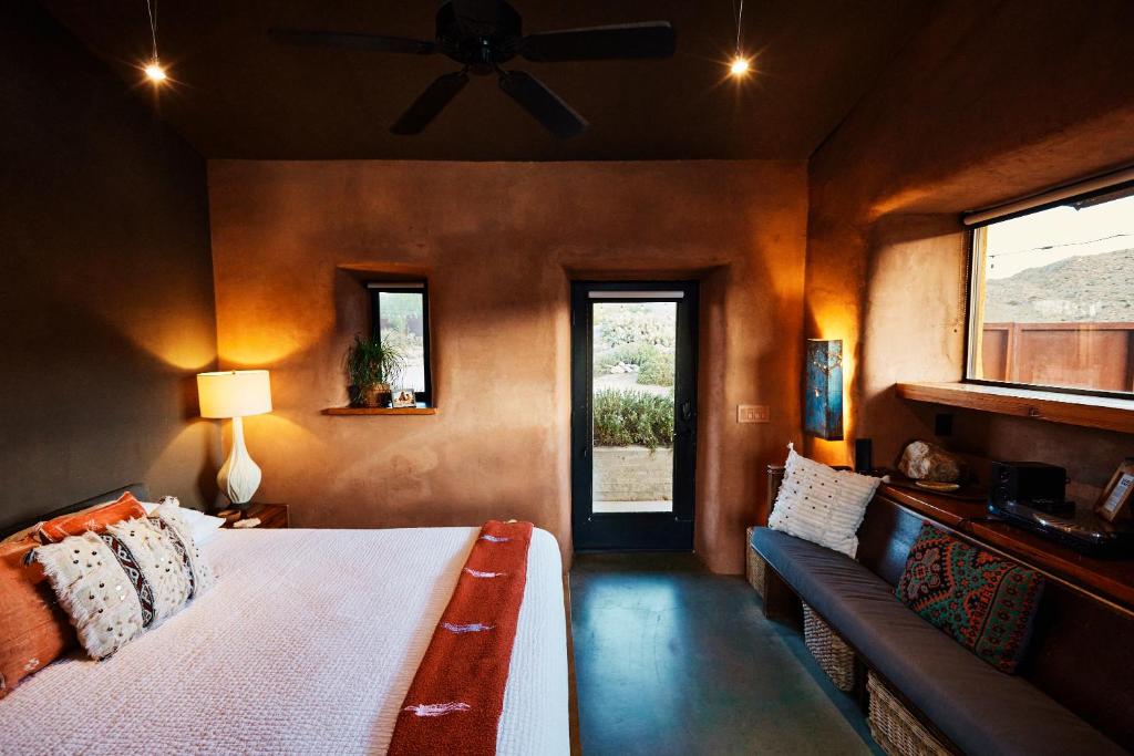 約書亞樹的住宿－Sacred Sands，一间卧室配有一张床、一张沙发和一个窗口