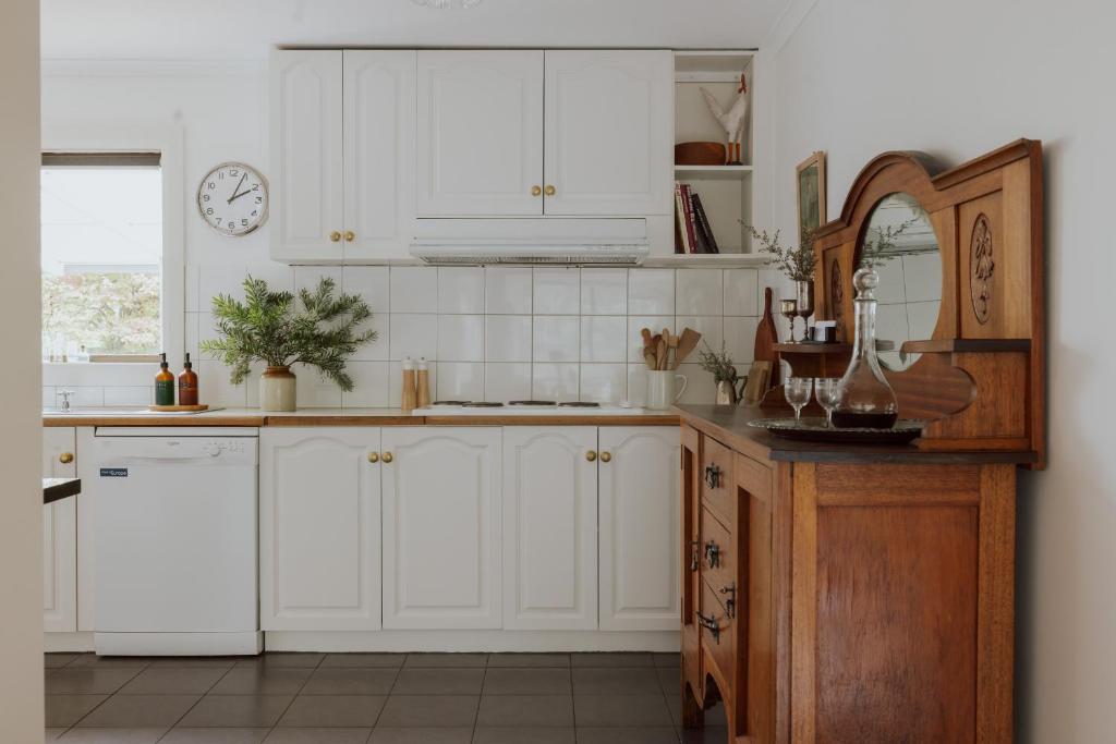 a kitchen with white cabinets and a mirror at Naivasha Cottage in Deloraine