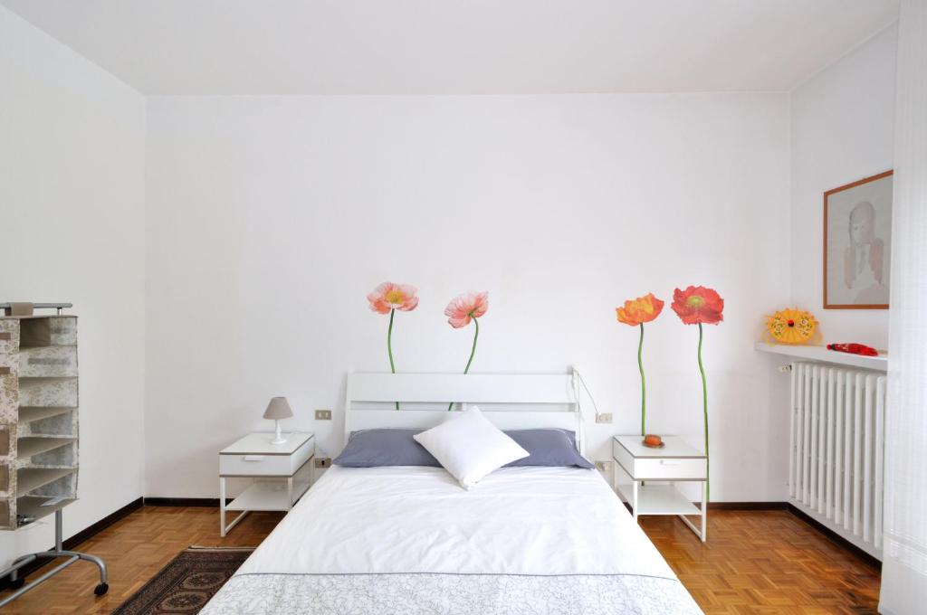 1 dormitorio con 1 cama blanca con flores en la pared en Brianza Relax, en Besana in Brianza