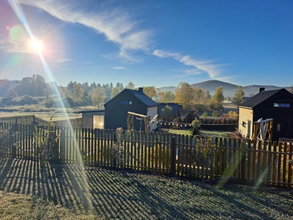 a wooden fence with the sun shining behind it at Bieszczadzkie BOHO stodoły z jacuzzi i sauna na wyłączność in Myczkowce
