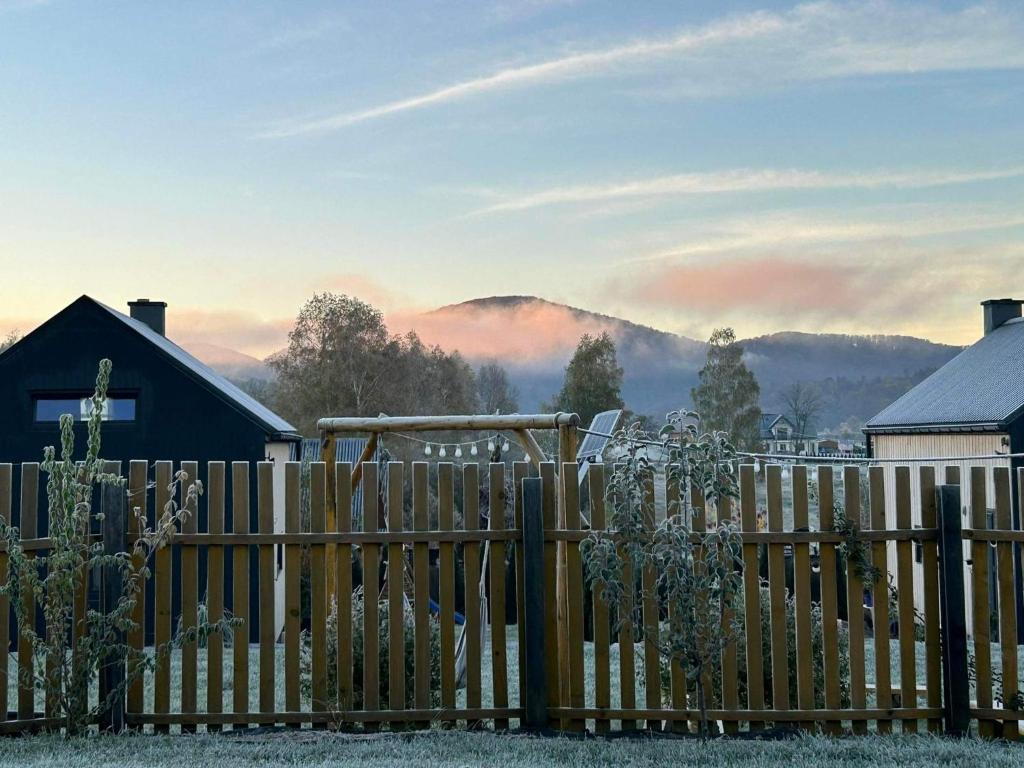 a wooden fence with a mountain in the background at Bieszczadzkie BOHO stodoły z jacuzzi i sauna na wyłączność in Myczkowce