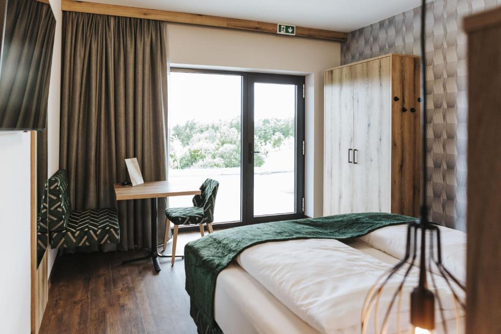 ein Hotelzimmer mit einem Bett, einem Schreibtisch und einem Fenster in der Unterkunft Kickmaier's in Kirchbach in Steiermark