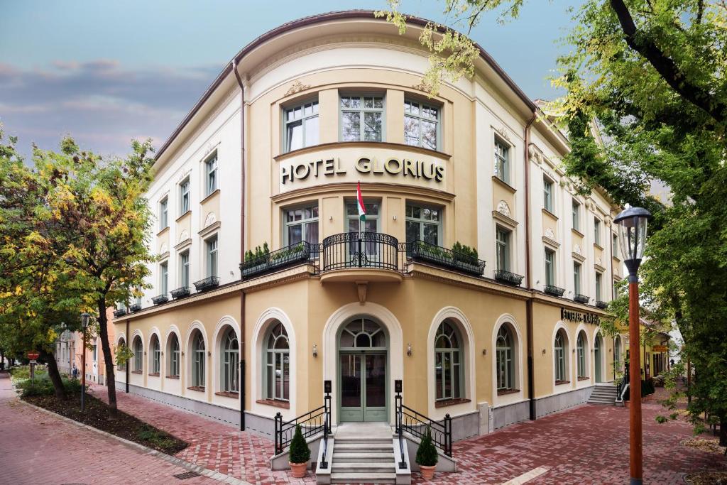 a large yellow building with a sign on it at Grand Hotel Glorius Makó in Makó