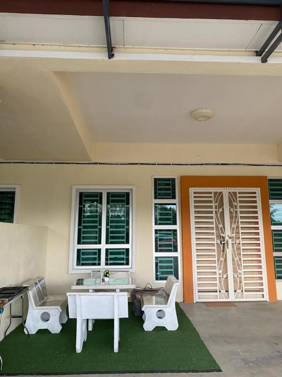 eine Terrasse mit einem weißen Tisch, Stühlen und Fenstern in der Unterkunft Cik Misi Homestay in Sik