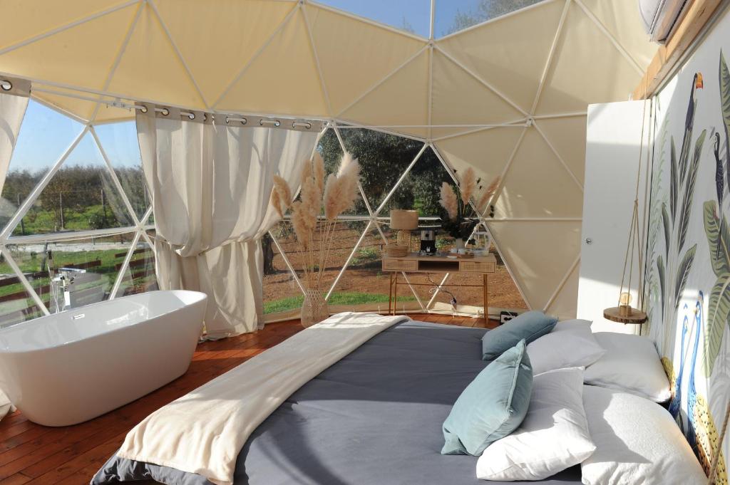a bedroom with a tub and a bed in a tent at Melograno Bubble Glamping in Vasanello