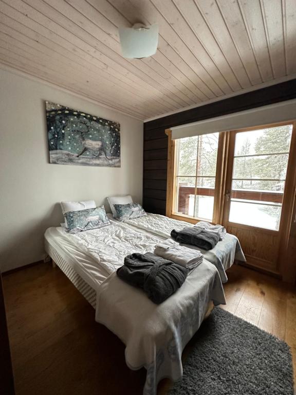 a bedroom with two beds and a large window at Villa Utsuntuisku in Levi