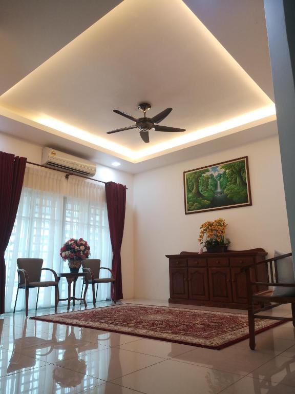 uma sala de estar com uma ventoinha de tecto e cadeiras em Kasih D'Sarina em Jitra