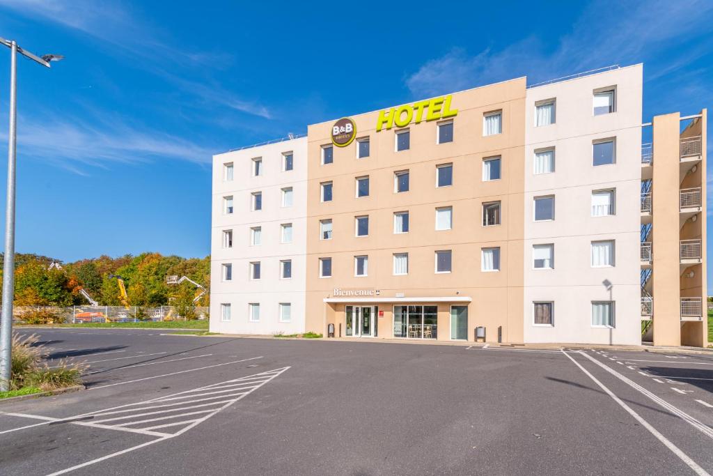 um hotel com um parque de estacionamento em frente em B&B HOTEL Lieusaint Carré Sénart em Lieusaint