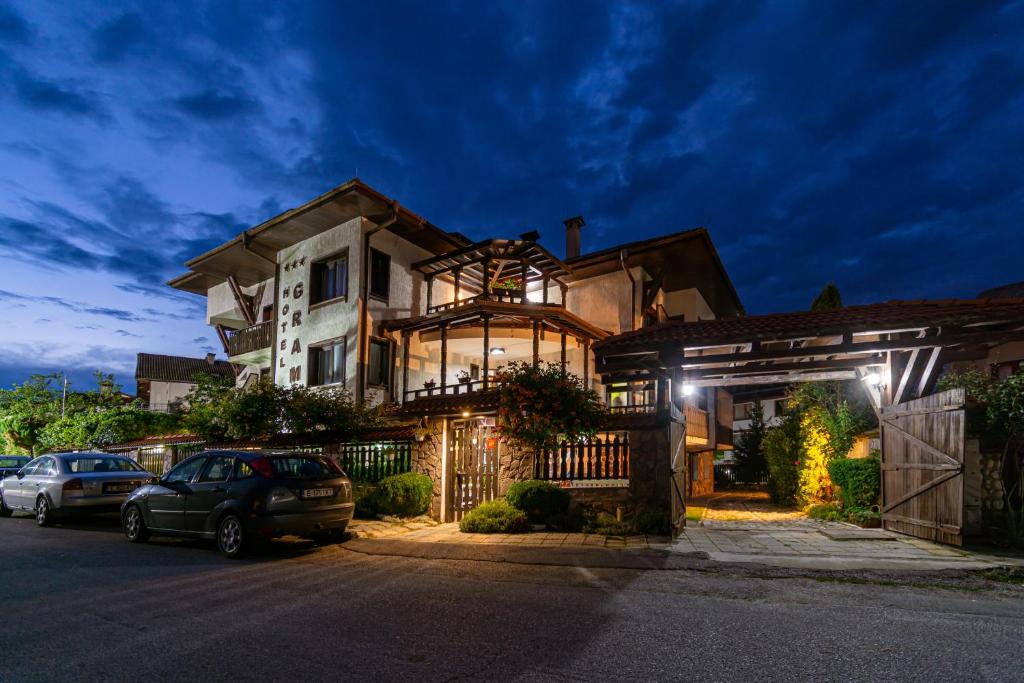 a large house with cars parked in front of it at Grami Hotel in Bansko