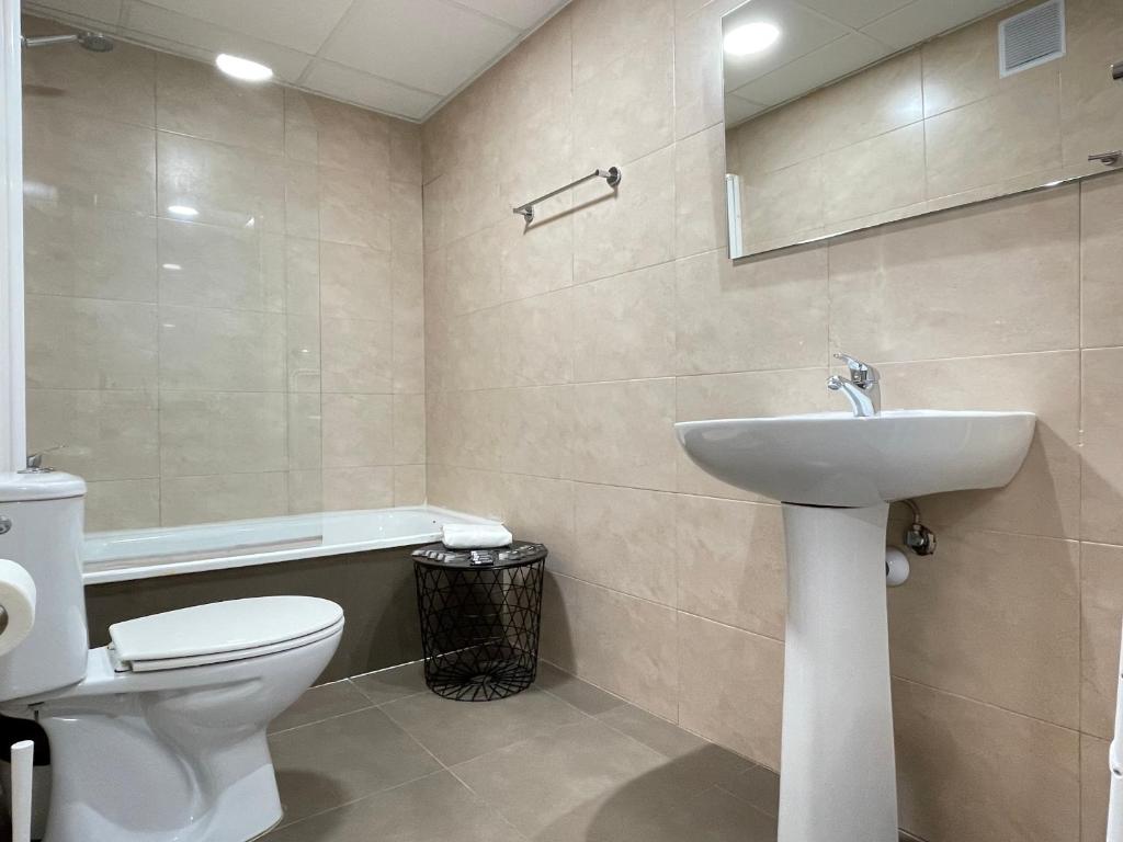 a bathroom with a white toilet and a sink at Apartamentos Venecia in Lloret de Mar