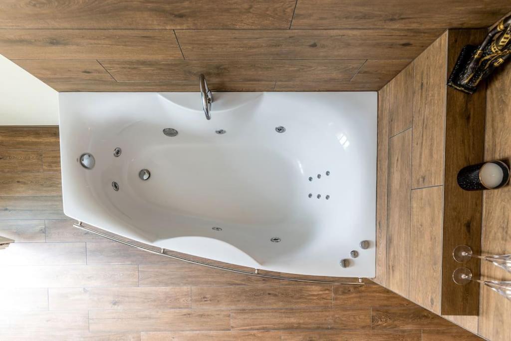 a white bath tub in a room with a wooden floor at Prabangūs apartamentai su džiakuzi (Jacuzzi) in Klaipėda